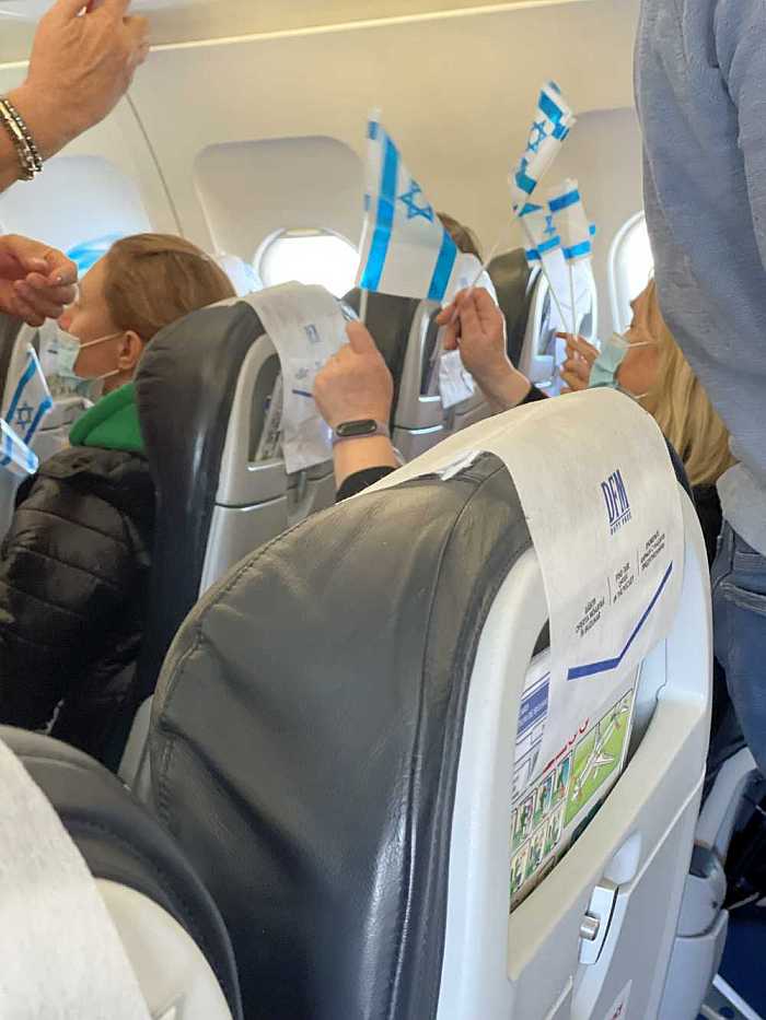 Ukrainian refugees on airplane with Israeli flags.